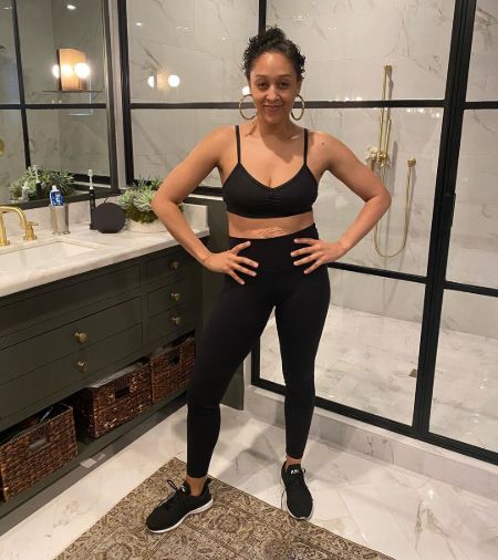 Tia Mowry poses for a picture in a black top and pants.